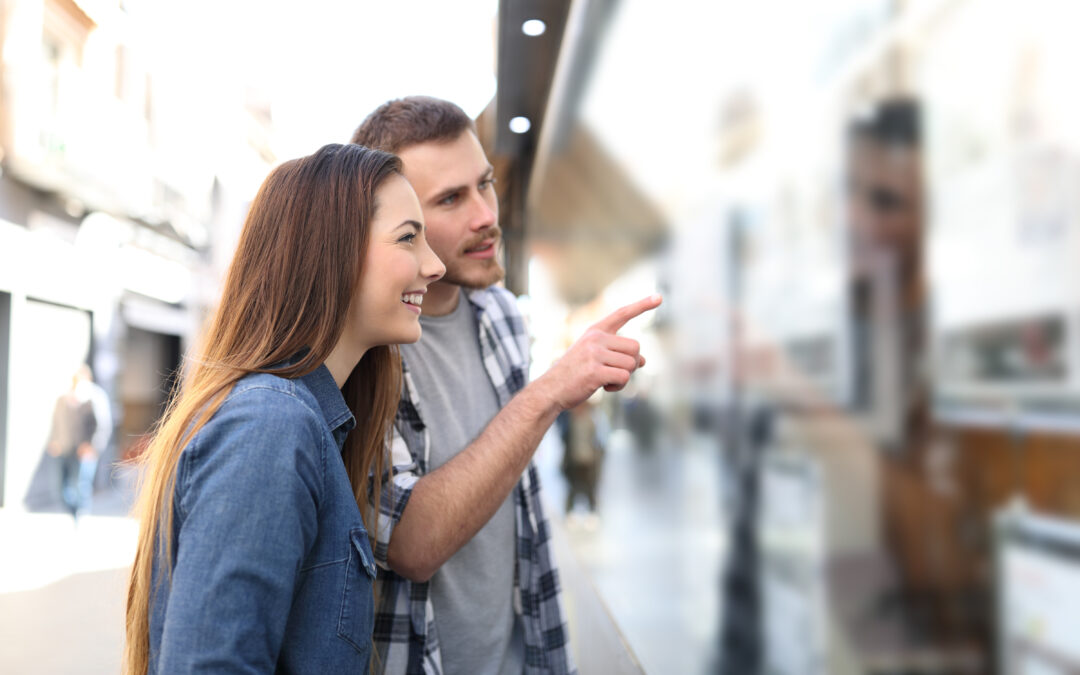 Jeune couple souriant consultant des annonces immobilières pour trouver un logement adapté