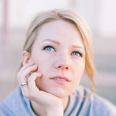 Portrait d'une femme pensive illustrant la réflexion sur une reconversion professionnelle dans l'immobilier inclusif.